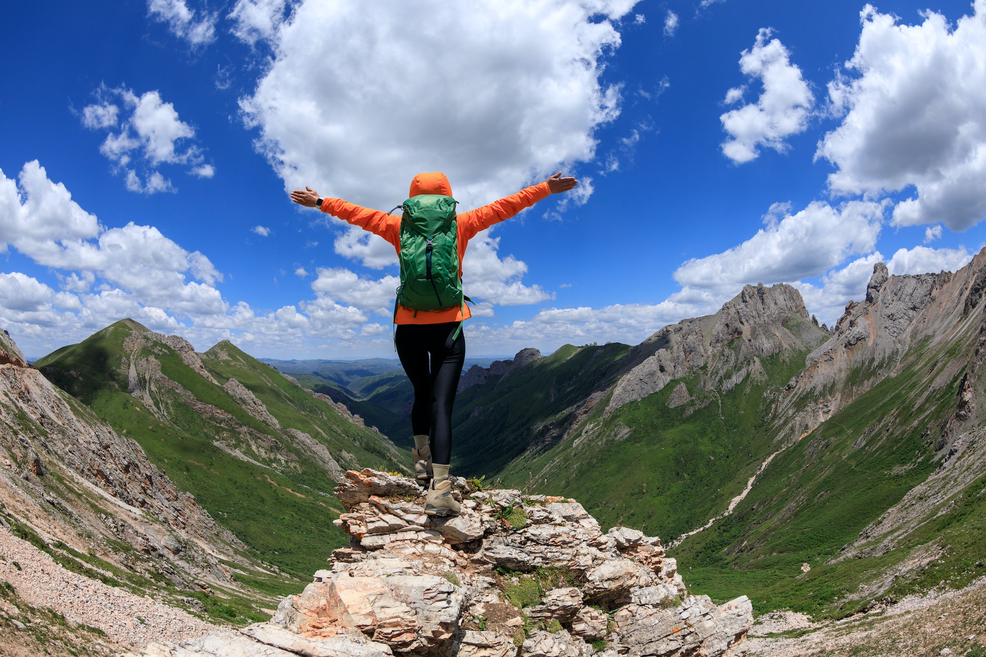Successful woman backpacker hiking on alpine mountain peak