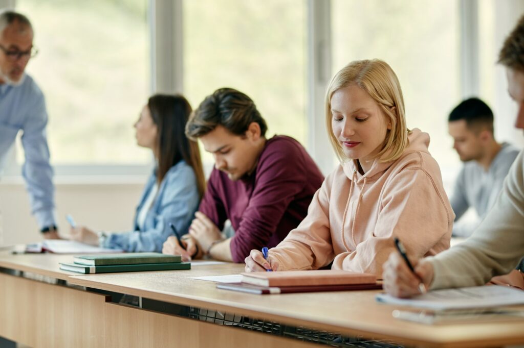 Female university student writing an exam in the classroom.